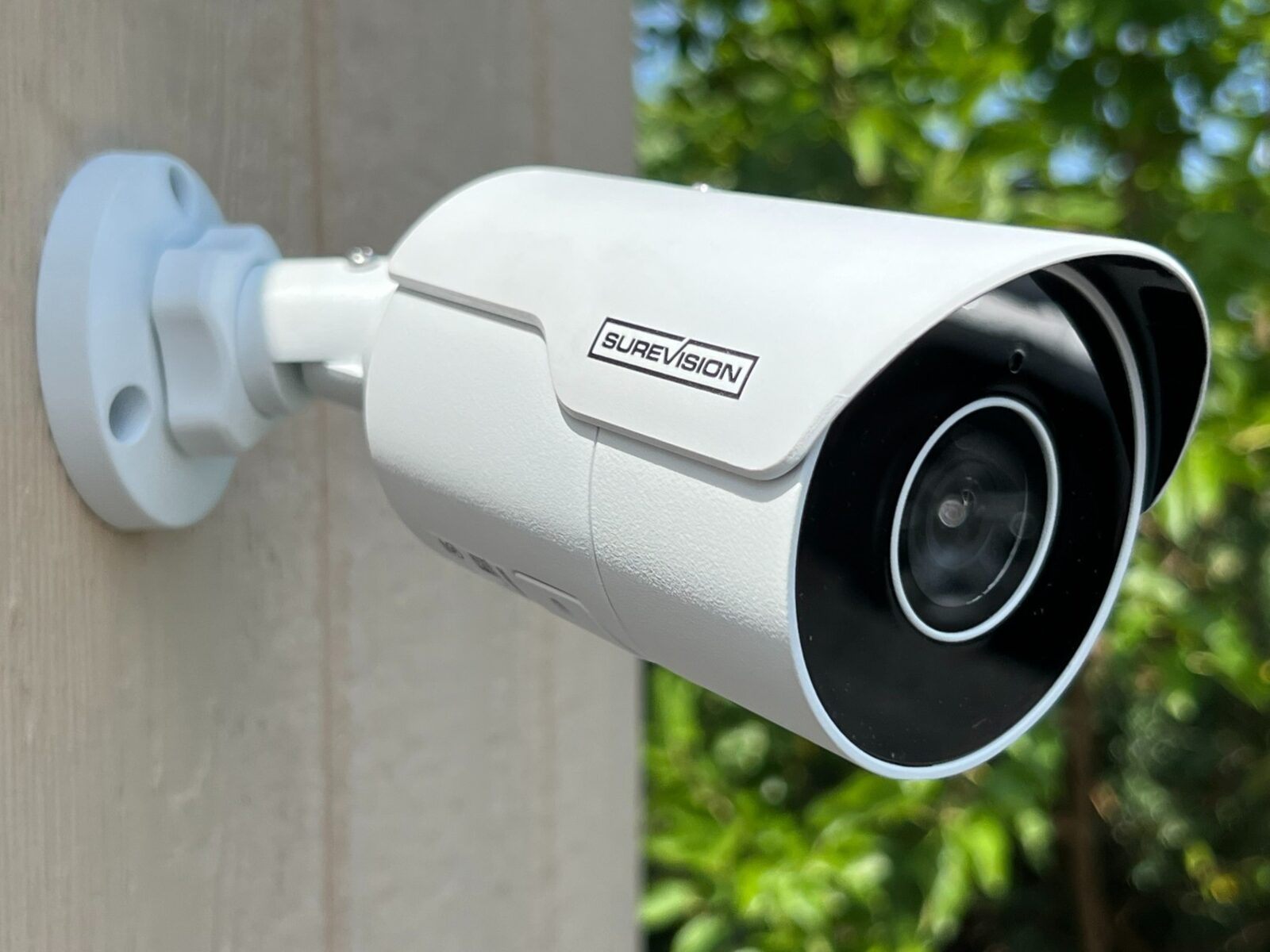 Professional white bullet camera installed on a house exterior in daylight